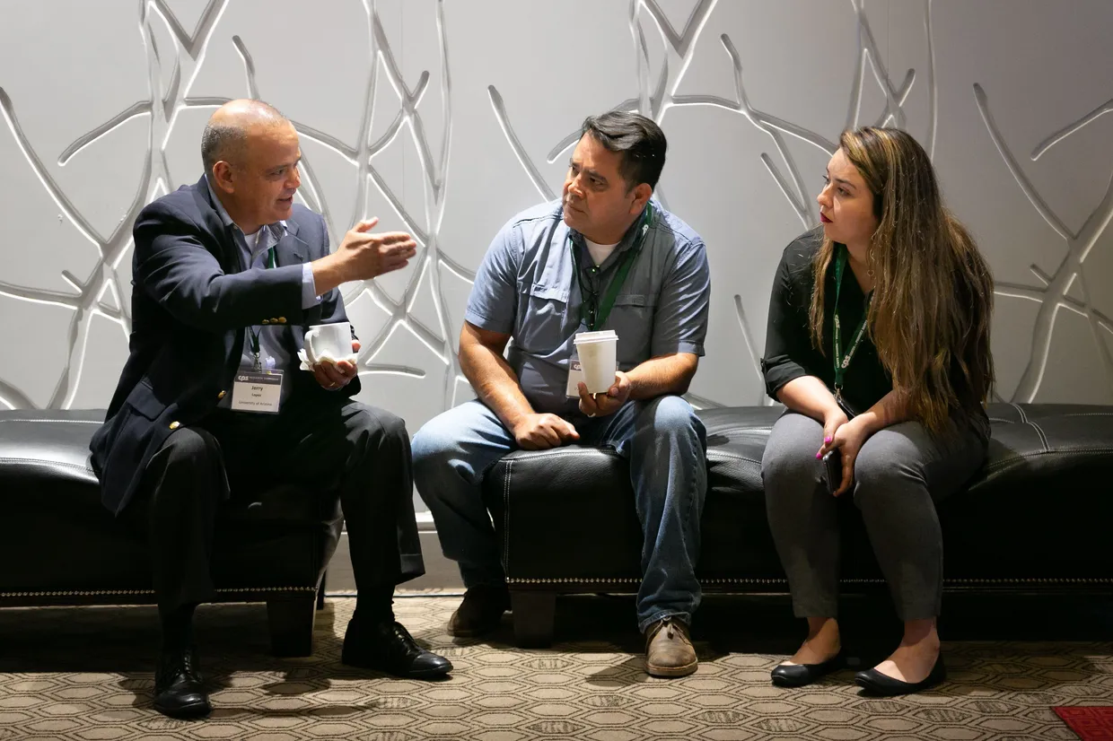 Three people talking together at CPS Symposium